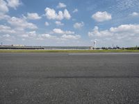 a jet airplane is on the runway in an airport area with a sky background and some clouds