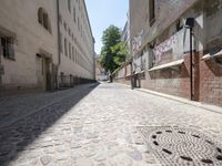 a narrow cobblestone street with graffiti all over it on one side and a red fire hydrant on the other