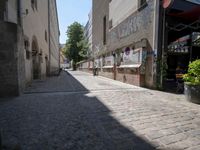 a narrow cobblestone street with graffiti all over it on one side and a red fire hydrant on the other