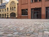 an empty street with brick walkways with lots of windows and bricks on it and people walking near to them