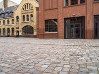 an empty street with brick walkways with lots of windows and bricks on it and people walking near to them