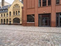 an empty street with brick walkways with lots of windows and bricks on it and people walking near to them