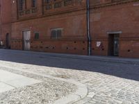 a man standing on the sidewalk in front of a brick building with a sign saying no parking