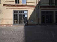 an old brick building is seen on a cobblestone street, but it's very hard to see