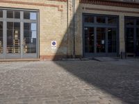 an old brick building is seen on a cobblestone street, but it's very hard to see