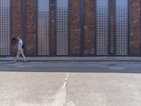 the young man is walking down the street on his skateboard in front of a brick building