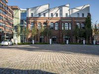 this photo shows a brick courtyard with trees and buildings surrounding it in front of the building