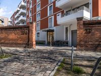 a brick patio in a courtyard next to a tall building with several balconies