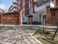 a brick patio in a courtyard next to a tall building with several balconies