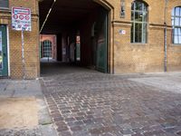 a brick walkway has a street sign and signs outside the doorway of an old building