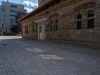 the back patio of a building with stone paving and an umbrella on top of it