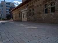 the back patio of a building with stone paving and an umbrella on top of it