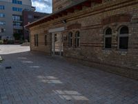 the back patio of a building with stone paving and an umbrella on top of it