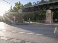 an overpass that is sitting above some traffic trees and some people and a motorcycle