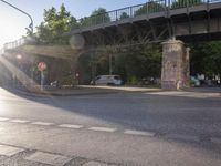 an overpass that is sitting above some traffic trees and some people and a motorcycle