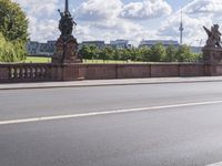 a person on a bicycle riding across a bridge with two statues on either side of the road