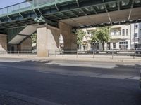 a street in front of a bridge with graffiti on it and cars parked beneath the road