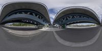 a fish eye view of a large bridge over a street filled with traffic and pedestrians