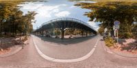 a 360 - view shot taken from the side of the street shows the traffic under a bridge