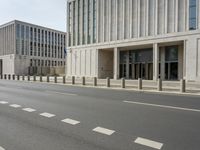 two large concrete buildings on the corner of a road with a line of traffic on either side