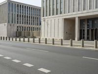 two large concrete buildings on the corner of a road with a line of traffic on either side