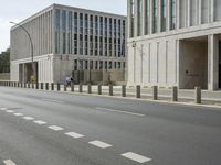 two large concrete buildings on the corner of a road with a line of traffic on either side