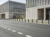 two large concrete buildings on the corner of a road with a line of traffic on either side