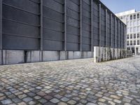 cobblestone floor with multiple sizes, in front of industrial style building and concrete wall