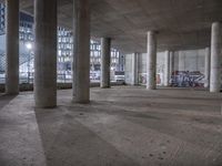 the ceiling of an empty building with graffiti and concrete pillars, the walls painted blue, and the floor