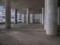 the ceiling of an empty building with graffiti and concrete pillars, the walls painted blue, and the floor