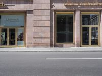 the sidewalk is lined with windows and signs on it's side of a building