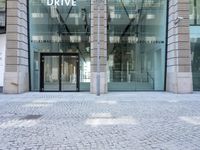 a parked bike is in front of a business building with glass walls and windows that read drive