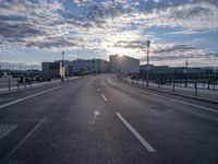 an empty highway leading into the sunset on a cloudy day with lots of cars driving past