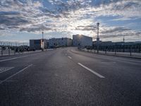 an empty highway leading into the sunset on a cloudy day with lots of cars driving past