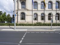 some flags are on the street outside of a building with windows and doors on the building