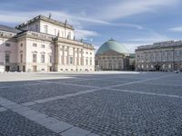 square with a church in front of the building and several other large buildings across from it