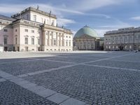 square with a church in front of the building and several other large buildings across from it