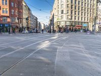 the people are waiting to cross the street from the tram station to the sidewalks