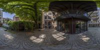 an upside down photograph of a small cafe by a cobble stone courtyard with trees