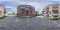 a fish eye lens shows a circular street scene with buildings in the background and a cobblestone walkway