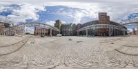 a fish eye photo showing a circular walkway and buildings in the background with a big blue sky