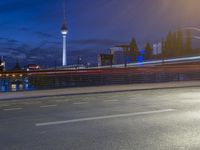 the skyline of berlin, germany is visible behind an empty street in this image, there's a bridge and tall buildings