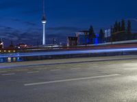 the skyline of berlin, germany is visible behind an empty street in this image, there's a bridge and tall buildings