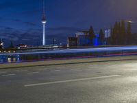 the skyline of berlin, germany is visible behind an empty street in this image, there's a bridge and tall buildings