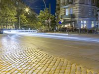 two rows of tables are at the street corner of the city center, in a blurry view of cars on the road