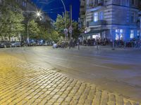 two rows of tables are at the street corner of the city center, in a blurry view of cars on the road