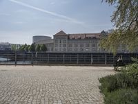 a man on a bench by a river looking over the bridge and buildings of the city