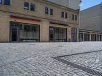 the sidewalk is paved with stones and has a bench in front of it, with no people inside