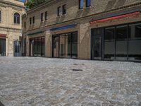 the sidewalk is paved with stones and has a bench in front of it, with no people inside