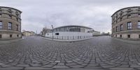 a large stone road with a circular building in the background and the entrance to a museum